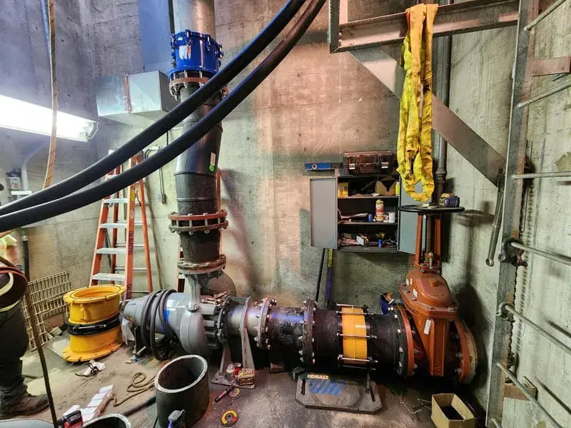 Large flanged pipework, a butterfly valve and an actuator inside a concrete pumping plant