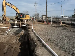 A white pipe laid along the bottom of a long open trench across a treatment plant site