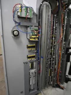 The open interior of a control panel showing rows of numbered terminal blocks and bundled field wiring