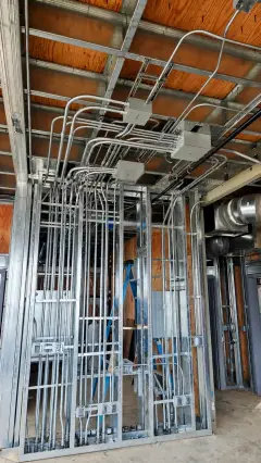 Runs of metal conduit and cable tray fixed to a timber ceiling structure during fit-out