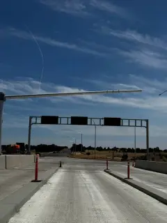 A steel gantry carrying changeable message signs spanning a paved truck lane