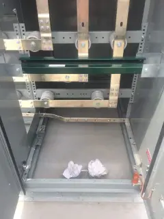 The empty interior of a metal switchgear enclosure showing copper bus bars and mounting rails