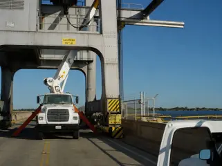 A boom truck with outriggers deployed underneath the legs of a gantry crane