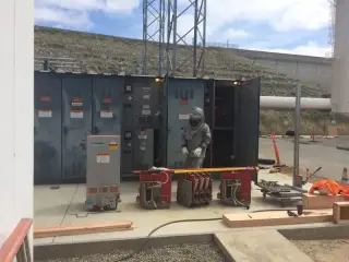 A row of tall grey metal-clad switchgear cubicles standing on a concrete pad ready to be installed