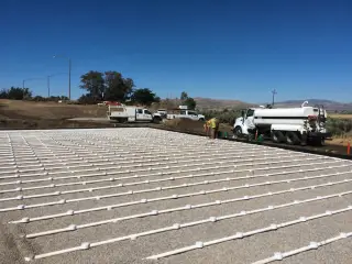 Long parallel rows of perforated distribution pipe laid out across a graded field