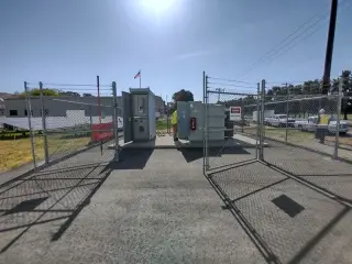 A finished electrical substation with metal-clad equipment standing behind a chain link security fence