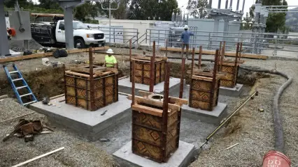 Square timber column forms with reinforcing steel projecting, set on new concrete pads at a substation site