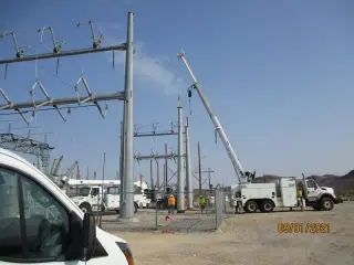 A crane and a line truck working among new galvanised steel structures at a desert substation