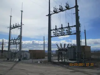 Steel substation structures carrying insulators and switches, with a low equipment building alongside