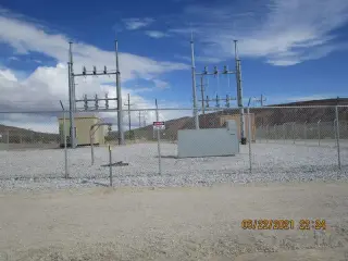A completed desert substation with steel structures, switches and equipment cabinets behind a fence