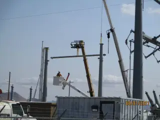 A worker in a lift bolting up galvanised steel structures at a substation under construction
