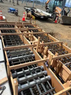 Rows of electrical conduit stub-ups rising through timber formwork and reinforcing steel before concrete is placed