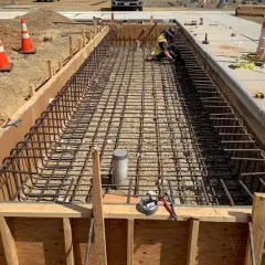 A long timber-formed foundation trench filled with a tied reinforcing steel cage, seen from above