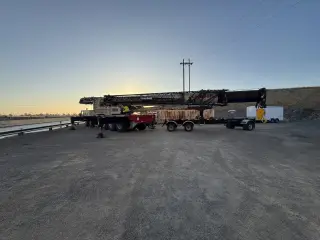 A mobile crane and trailers parked on an access road at sunset