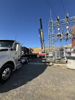 A substation structure carrying insulators and bus, with a tractor unit parked in the foreground