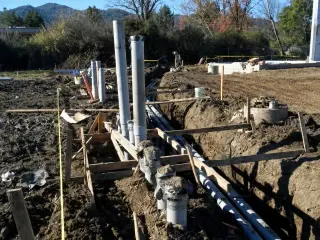 Grey electrical conduit running along a formed trench with vertical stub-ups at intervals