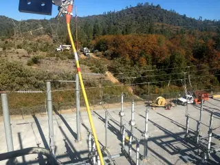 Steel lattice substation structures carrying switches and insulators, seen from below against a clear sky