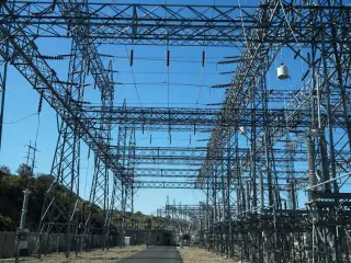 A long view down a high-voltage switchyard between rows of steel lattice structures and insulator strings