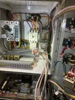 An open control panel showing relays, terminal blocks and neatly routed control wiring