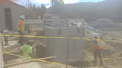 A crew working around two large precast concrete vaults inside a taped-off work area