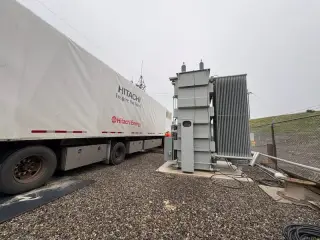 A large electrical unit on a covered semi-trailer being delivered to a substation site