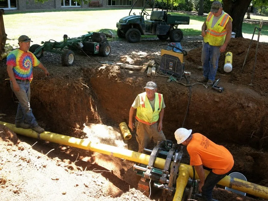 Crews fusing and laying pipe in an open trench